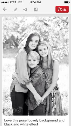 black and white photograph of three girls hugging each other in front of a field with trees