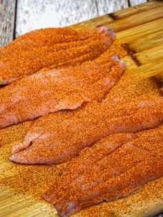 a wooden cutting board topped with meat and seasoning