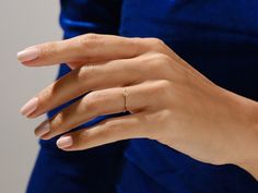 a woman's hand with a gold ring on her left hand and a blue velvet dress