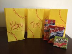 three yellow bags with writing on them sitting on a table next to some snacks and candy