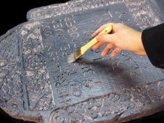 a person using a brush to paint on a decorative object