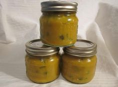 four jars filled with yellow pickles sitting on top of a white cloth