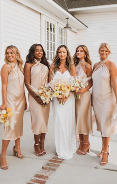 the bridesmaids are all dressed in nude colored dresses and holding bouquets together