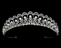 Pearl and Rhinestone Wedding Tiara This beautiful tiara will provide classic elegance to your bridal ensemble. The silver plated design is adorned with lustrous pearls and sparkling crystal rhinestones. This headpiece will be a memorable addition to your modern wedding look! Size: 1 1/4" High at its peak. Color: Silver/Light ivory. Style: T56300. Please allow about a week for delivery. Shipping Policy. Return Policy. Cosplay Crown, Bride Tiara, Pearl Tiara, Beautiful Tiaras, Regal Design, Headpiece Jewelry, Rhinestone Tiara, Wedding Look, Light Ivory