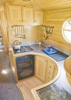 the interior of a small kitchen with wood paneling and stainless steel stove top oven