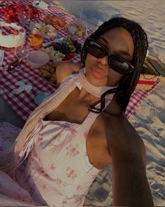 a woman sitting on the beach with food and drinks