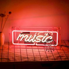 a neon sign that says music on it next to a vase with flowers in it