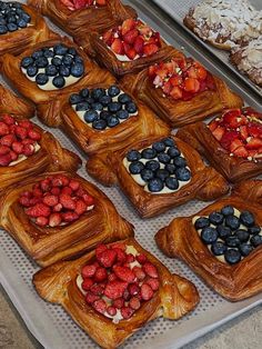 many pastries are arranged on a tray with berries and blueberries in the middle