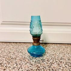 a blue glass candle holder sitting on top of a marble counter next to a white door