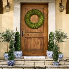 the front door is decorated with blue and white vases, potted plants, and a wreath