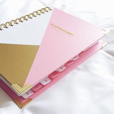 three notebooks stacked on top of each other with gold and pink paper attached to them