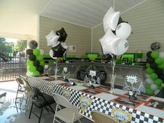 a long table with balloons and pictures on it at a race car themed birthday party