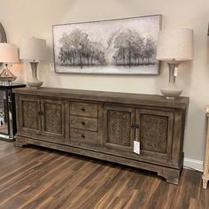 a large piece of furniture on display in a room with wood flooring and lamps