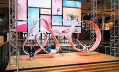 the stage is set up for an event with people sitting on it and large pink letters