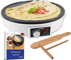 an electric crepe maker with two wooden spatulas and a cookbook