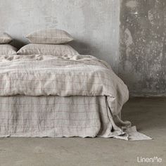 a bed with two pillows on top of it next to a wall and cement floor