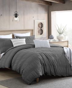 a bed with grey comforter and pillows in a room