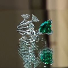 two pieces of jewelry sitting on top of a glass table next to eachother