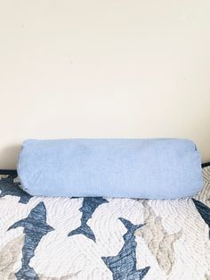 a blue pillow sitting on top of a bed next to a white and black wall