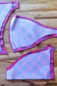 two pieces of pink and blue swimsuit sitting on top of a wooden floor next to each other