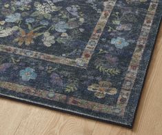 a blue rug with floral designs on the top and bottom, sitting on a wooden floor