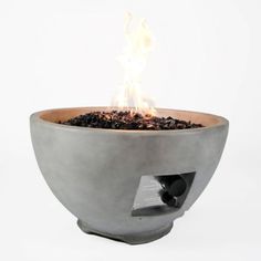 an outdoor fire pit is shown with flames coming out of the top, and black rocks in the bottom