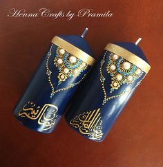 two blue candles with gold designs on them are sitting on a table next to each other