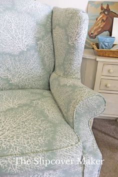 a blue chair with white coral print on it in a room next to a dresser