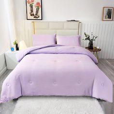 a bed with a purple comforter and white rug on the floor next to it