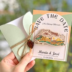 someone holding up a save the date card with a leaf on it and a tag attached to it