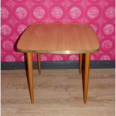 a small wooden table against a pink wall