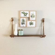 a shelf with three pictures hanging on it and two vases sitting next to each other