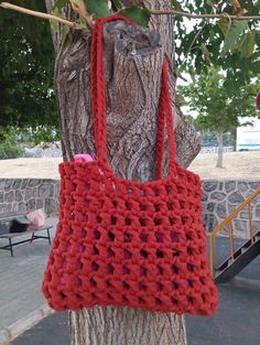 a red crocheted bag hanging from a tree