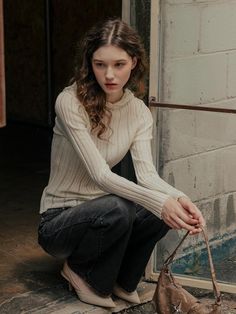 a young woman sitting on the ground with her purse