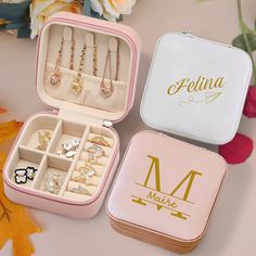 three personalized jewelry boxes sitting next to each other on a table with flowers in the background