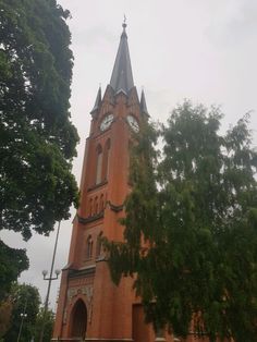 an old building with a steeple and clock on the front is surrounded by trees