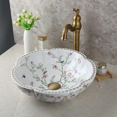 a bathroom sink with flowers on it and a faucet in the corner next to it