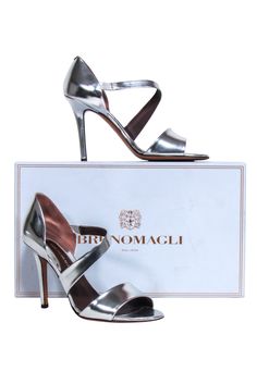 Take your style game up a notch with these silver metallic Brunomagli pumps! With their open toe and wrap around detail, it will be a night to remember! Style them with a little black dress to set off the evening with a spark! Size 6.5 (IT 36.5) Made in Italy 100% Leather Slip on Open toe Comes with dustbag and box Heel height 4" Chic Silver Open Heel Shoes, Chic Silver Open Heel Heels, Chic Metallic Silver Heels With Heel Strap, Silver Sandals With Padded Heel For Night Out, Chic Metallic Silver Open Toe Heels, Chic Silver Heels With Wrapped Heel, Metallic Pointed Toe Sandals For Evening, Metallic Pointed Toe Evening Sandals, Metallic Heels With Branded Heel Counter For Spring