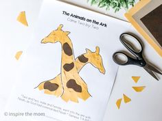 the paper cut out of two giraffes is next to scissors and glue