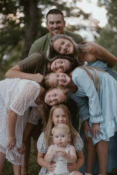 a group of people standing next to each other posing for a photo in front of trees