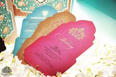 three different colored wedding cards on top of white flowers