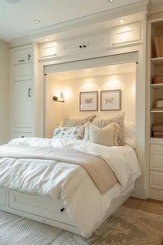 a white bed sitting in a bedroom next to a book shelf filled with books and pillows