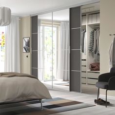 a bedroom with a bed, chair and mirrored closet doors