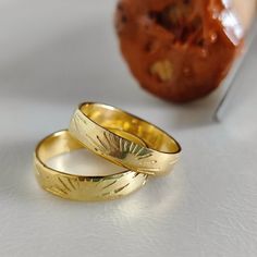 two gold wedding rings sitting next to each other