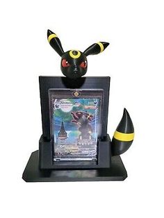 a black and yellow figurine sitting in front of a computer monitor with an image of pikachu on it