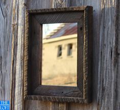 a mirror hanging on the side of a wooden door with an old building in the background