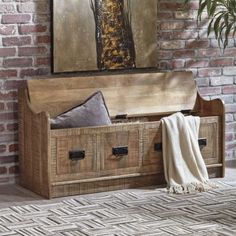 a wooden bench with two drawers and a blanket on the floor in front of a brick wall