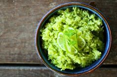 a blue bowl filled with green rice on top of a wooden table