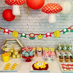 a table topped with cupcakes and cakes next to paper lanterns hanging from the ceiling