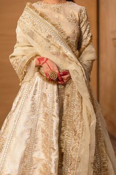 a woman in a white and gold lehenga with red accessories on her hand